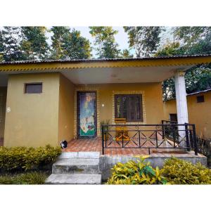 a yellow house with a cat sitting in front of the door at Tamu Homestay in Jhawāni