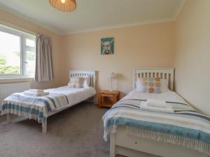 a bedroom with two beds and a window at Bro Mebyd in Criccieth