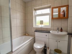 a bathroom with a tub and a toilet and a sink at Bro Mebyd in Criccieth +20 photos