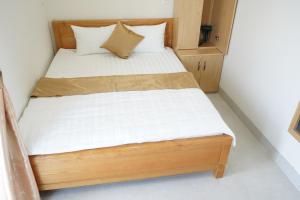 a bed in a small room with white sheets and pillows at Morgan Hotel in Ấp Bình Hưng