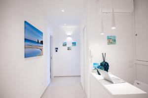 a white hallway with a laptop on a white table at Lumina Rooms in Torre dell'Orso +24 photos
