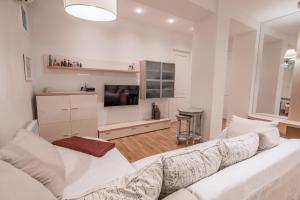 a living room with a white couch and a tv at Hyacinth House in Tbilisi City