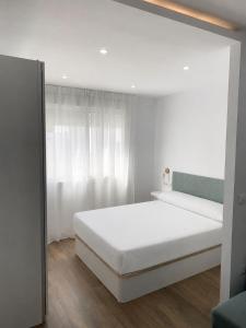 a white bedroom with a white bed and a window at apartamento en centro in Chipiona