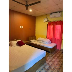 a room with two beds and a red curtain at Tamu Homestay in Jhawāni