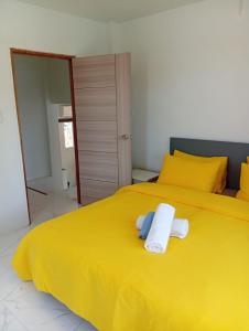 a yellow bed with two towels on top of it at Stylish 1BR Retreat with Workspace & Hammock in Hinkong