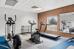 a gym with treadmills and ellipticals and a mirror at Comfort Inn & Suites FtJackson Maingate in Columbia