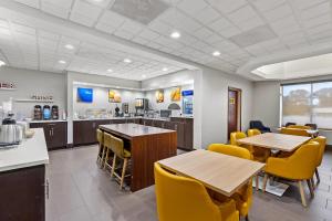 a restaurant with tables and yellow chairs and a counter at Comfort Inn & Suites FtJackson Maingate in Columbia