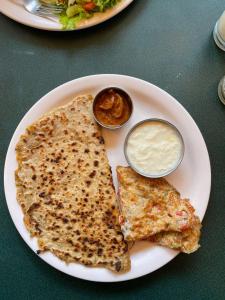 a plate of food with two pancakes and sauce at Hotel bright house in Calangute