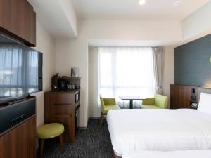 a hotel room with a bed and a tv and a table at Comfort Hotel ERA Kyoto Toji in Kyoto