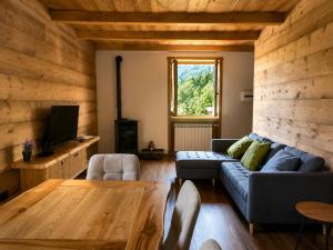 a living room with a blue couch and a wooden wall at SkyWood Chalet, Panoramic Mountain and Lake Views in Mello