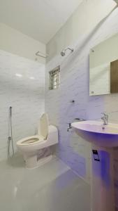 a white bathroom with a toilet and a sink at Hotel Sunrise Int in Dhaka