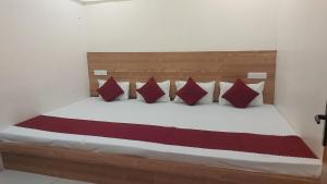 a bedroom with a bed with red and white pillows at Hotel Gokul in Ujjain