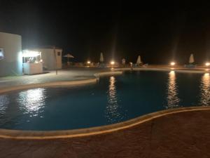 a swimming pool at night with lights at Diana Beach Villa spacious detached فيلا واسعه مستقله ديانا ONLY FAMILIES بيتش in Dawwār al Ḩajj Aḩmad +34 photos