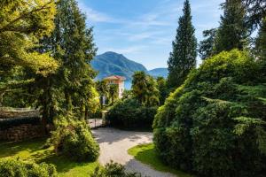 a garden with trees and a building in the background at Il Lavatoio in Cissano