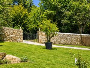 a garden with a stone fence and a tree in the grass at Corte Villa Donati in Cissano +27 photos
