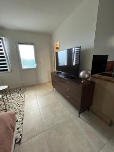 a living room with a flat screen tv on a dresser at Piscine chauffée partagée avec terrasse privative in Joué-lès-Tours