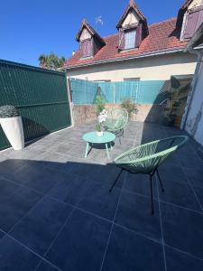 a patio with two chairs and a table and a fence at Piscine chauffée partagée avec terrasse privative in Joué-lès-Tours