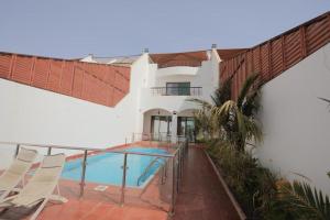 a house with a swimming pool and chairs on a balcony at Rose Beach 4 Durrat Alarous in Durat Alarous