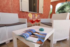 a table with two glasses of wine and a magazine on it at Helios Rooms in Quartu SantʼElena +6 photos
