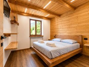 a bedroom with a bed in a wooden house at SkyWood Chalet, Panoramic Mountain and Lake Views in Mello