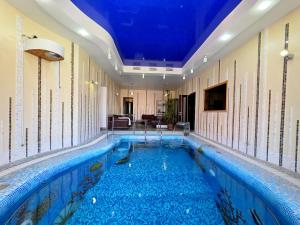 a swimming pool in a room with a blue ceiling at Вілла з 6 Спальнями Басейн Більярд Сауна BBQ Укриття in Odesa