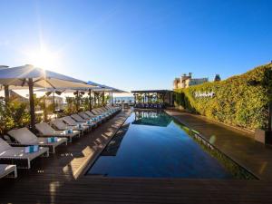 a pool with lounge chairs and umbrellas on a deck at Sofitel Barcelona Skipper in Barcelona