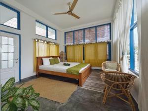 a bedroom with a bed and a chair and windows at Phoenix house ahangama in Ahangama