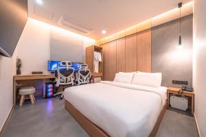 a bedroom with a large white bed and a desk and a desk at Giverny Hotel in Gyeongju