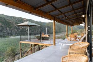 a deck with a table and chairs and an umbrella at Nicara Luxury Ecocabin Honeypunch in Keysers