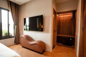 a bedroom with a chair and a tv on a wall at Nhiên Hotel in Ho Chi Minh City +11 photos