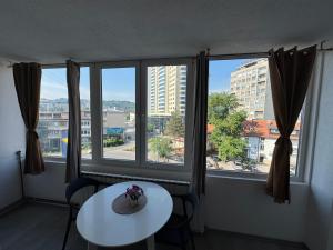 a room with a table and two windows with a view at Apartman Tuzla in Tuzla