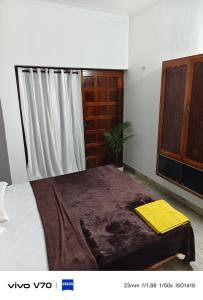 a bedroom with a bed with a yellow blanket on it at Easystayhomestay in Kunnamangalam