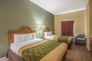 a hotel room with two beds and a chair at Econo Lodge Valdosta Mall Area in Valdosta +22 photos