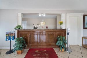 a lobby with a large wooden counter with two plants at Econo Lodge Thomaston in Thomaston