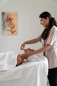 a woman is cutting a womans face on a bed at Zahir Rooms & Wellness srls in Trapani