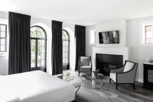 a white bedroom with a bed and a fireplace at Frontenac Club, an Ascend Collection Hotel in Kingston