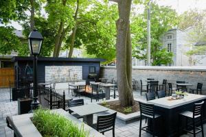 a patio with tables and chairs and a fireplace at Frontenac Club, an Ascend Collection Hotel in Kingston