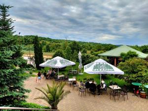 a group of people sitting at tables under umbrellas at Deny Inn Harmony in Zărneşti