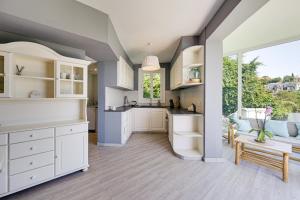 a kitchen with white cabinets and a large window at Chillout House with heated pool 29 C Sea & Mountain view in Santa Susanna