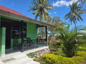 a green house with chairs and palm trees at Hotel Puma Bungalow in Huu