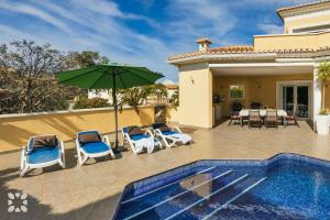 a patio with chairs and an umbrella next to a swimming pool at Villa Esplendida by Abahana Villas in Ifach +19 photos