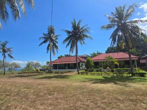 a building with palm trees in front of it at Hotel Puma Bungalow in Huu