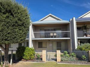 an apartment building with a fence and a tree at Getaway, Unit 20 Seafront Estate in Jurien Bay