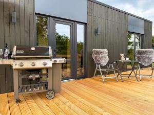 a barbecue on a deck with a table and chairs at FewoCrew Devils Cabin Premium Tiny House nahe Teufelsmauer in Wienrode