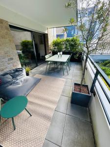 a patio with a table and a tree on a balcony at L'Hermine terrasse et parking, 500 plage in Concarneau +35 photos