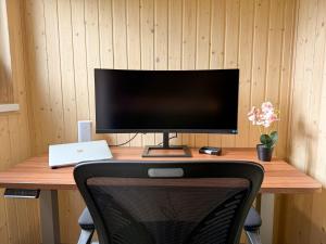 a computer monitor sitting on top of a wooden desk at FewoCrew Devils Cabin Premium Tiny House nahe Teufelsmauer in Wienrode