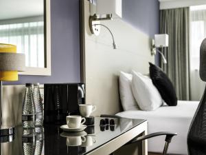 a hotel room with a bed and a table with cups at Mercure Manchester Piccadilly Hotel in Manchester