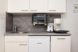 a kitchen with white cabinets and a sink and a microwave at Kirchenplatz 6 Apartment 18 Atlantic in Warnemünde