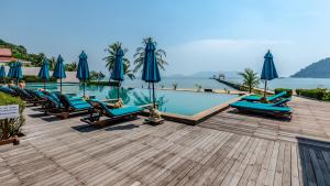 a swimming pool with blue lounge chairs and umbrellas at The Sea View Residence in Ban Bang Bao
