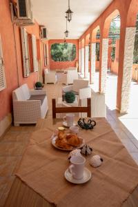 a table with cups and plates of food on it at Helios Rooms in Quartu SantʼElena
